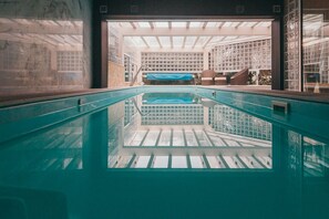 An indoor swimming pool with a view of a modern building with glass walls and a skylight. - Joy Beach House (Marinha Grande)