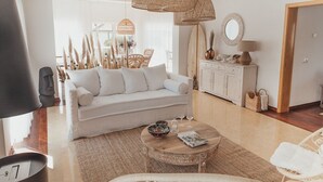 Ein modernes Wohnzimmer mit einem weißen Sofa, Korbmöbeln und einem Holztisch.