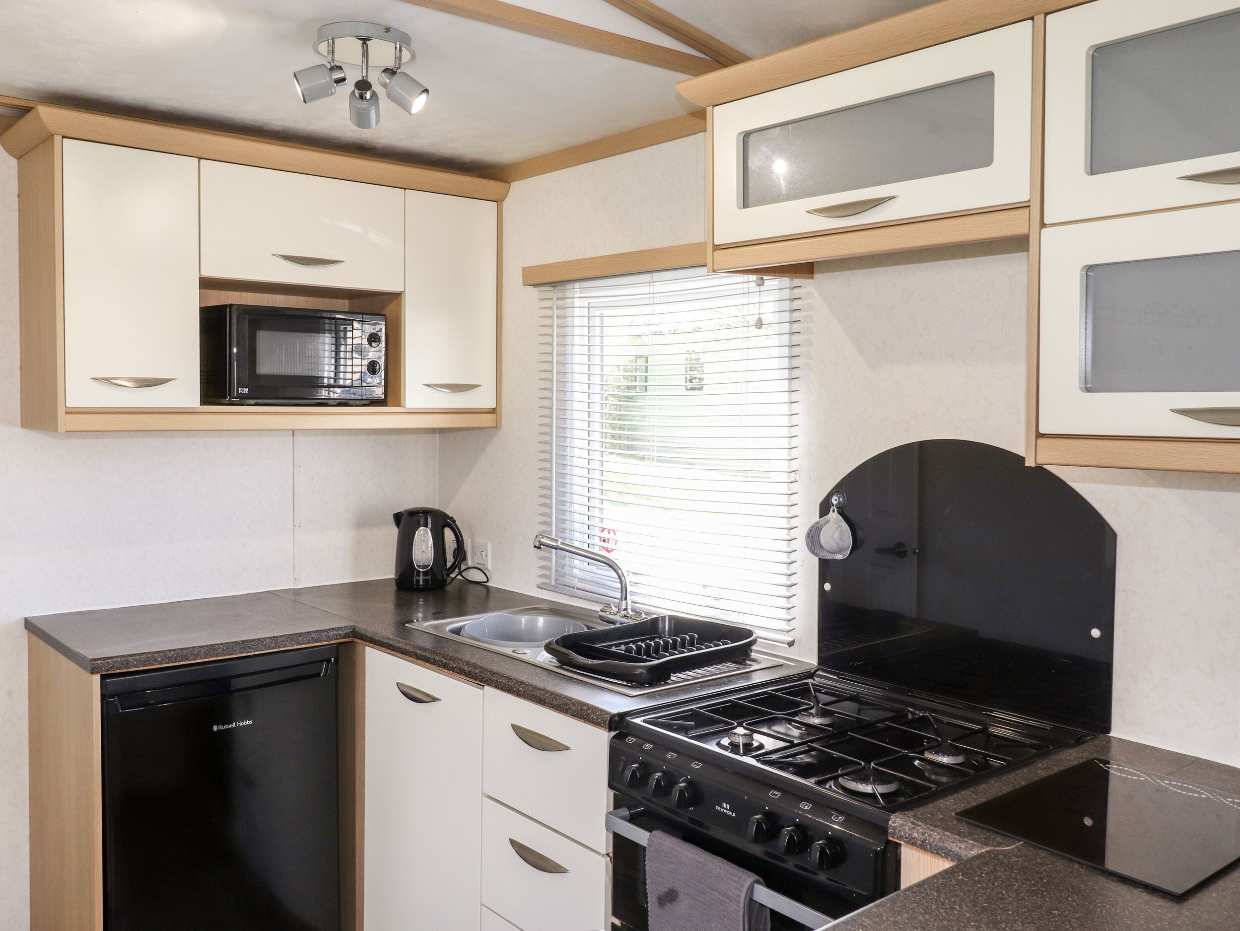 A compact kitchen with a built-in microwave, a stove, and a dishwasher.