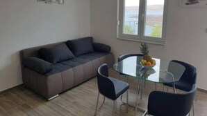 A modern living room with a sofa, a glass dining table, and chairs. There is a window with a view of the outdoors. - BEST VIEW APARTMENTS CESARICA - DODO (Cesarica)