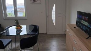 A modern living room with a glass dining table, black chairs, a wooden cabinet, and a flat-screen TV. - BEST VIEW APARTMENTS CESARICA - DODO (Cesarica)