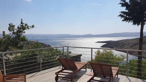 A deck with wooden furniture and a table set for a meal, overlooking a body of water and distant hills. - BEST VIEW APARTMENTS CESARICA - DODO (Cesarica)