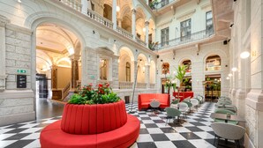 Un hall d’entrée spacieux avec un sol à carreaux, des sièges rouges et de nombreux balcons.