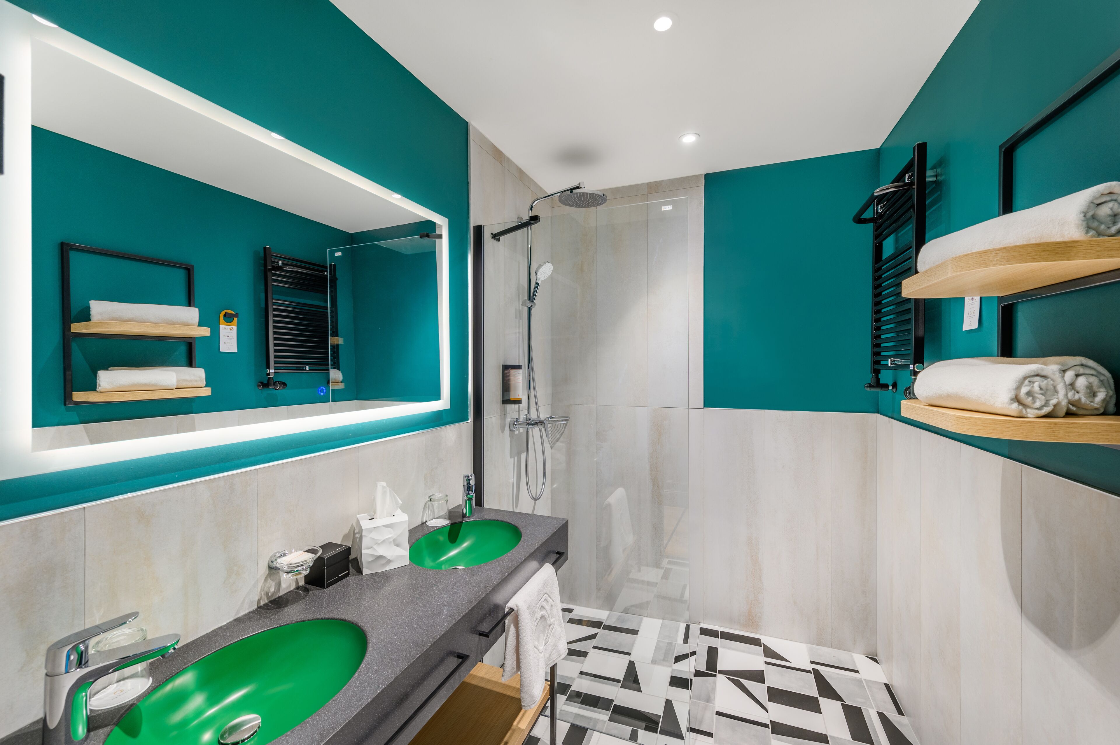 A modern bathroom with a green sink, a large mirror, a shower, and a towel rack.
