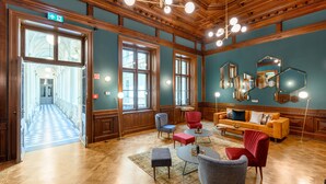Un hall d’entrée spacieux, doté de parquets en bois, de grandes fenêtres et d’un espace salon aménagé avec des meubles modernes et classiques.