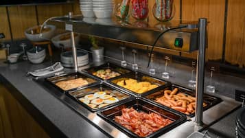 A buffet with various food items including eggs, ham, and hot dogs.