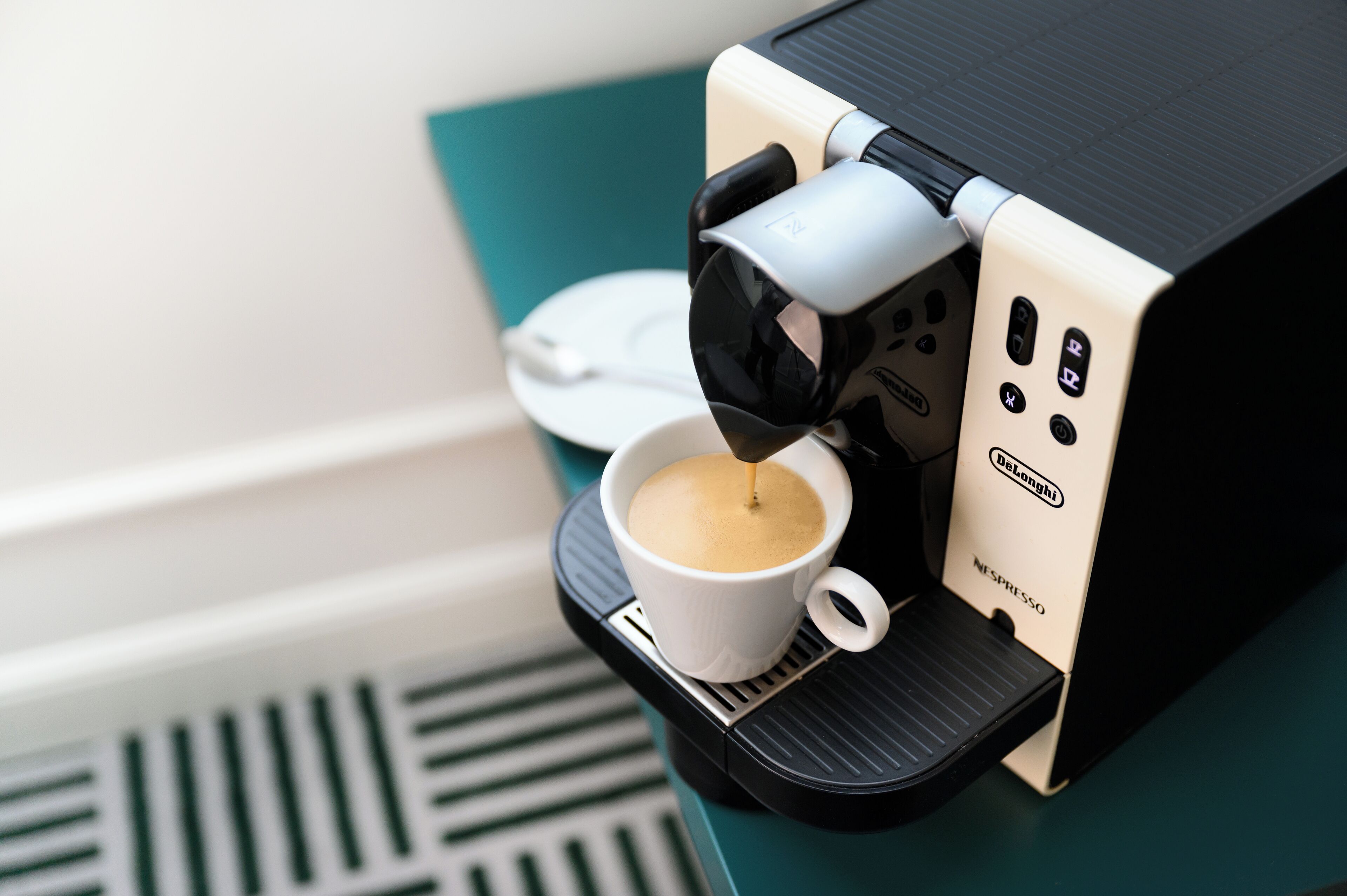 A DeLonghi Nespresso coffee machine dispensing coffee into a white cup.