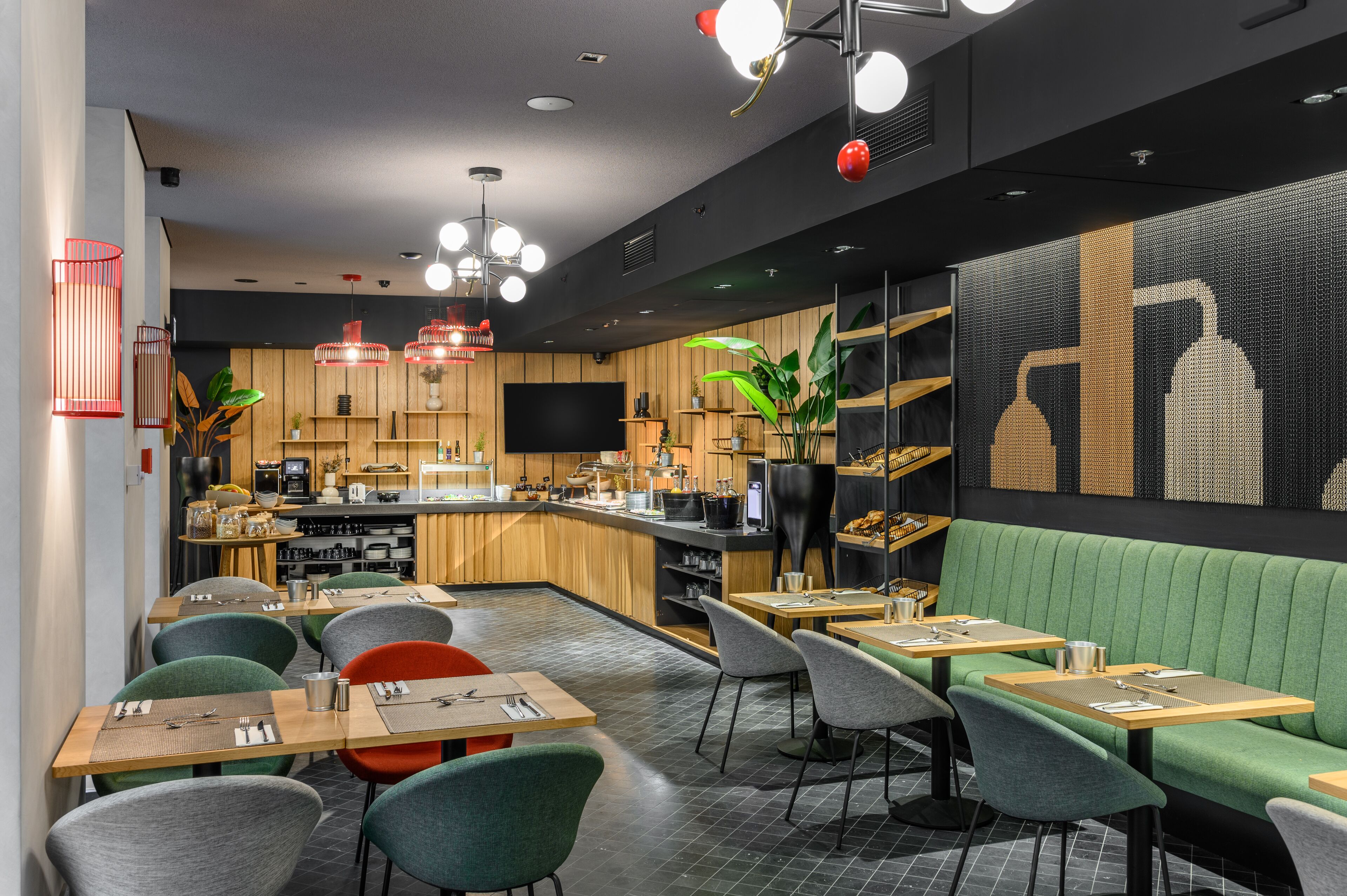 A modern restaurant with a bar area, green upholstered seating, and a variety of lighting fixtures.
