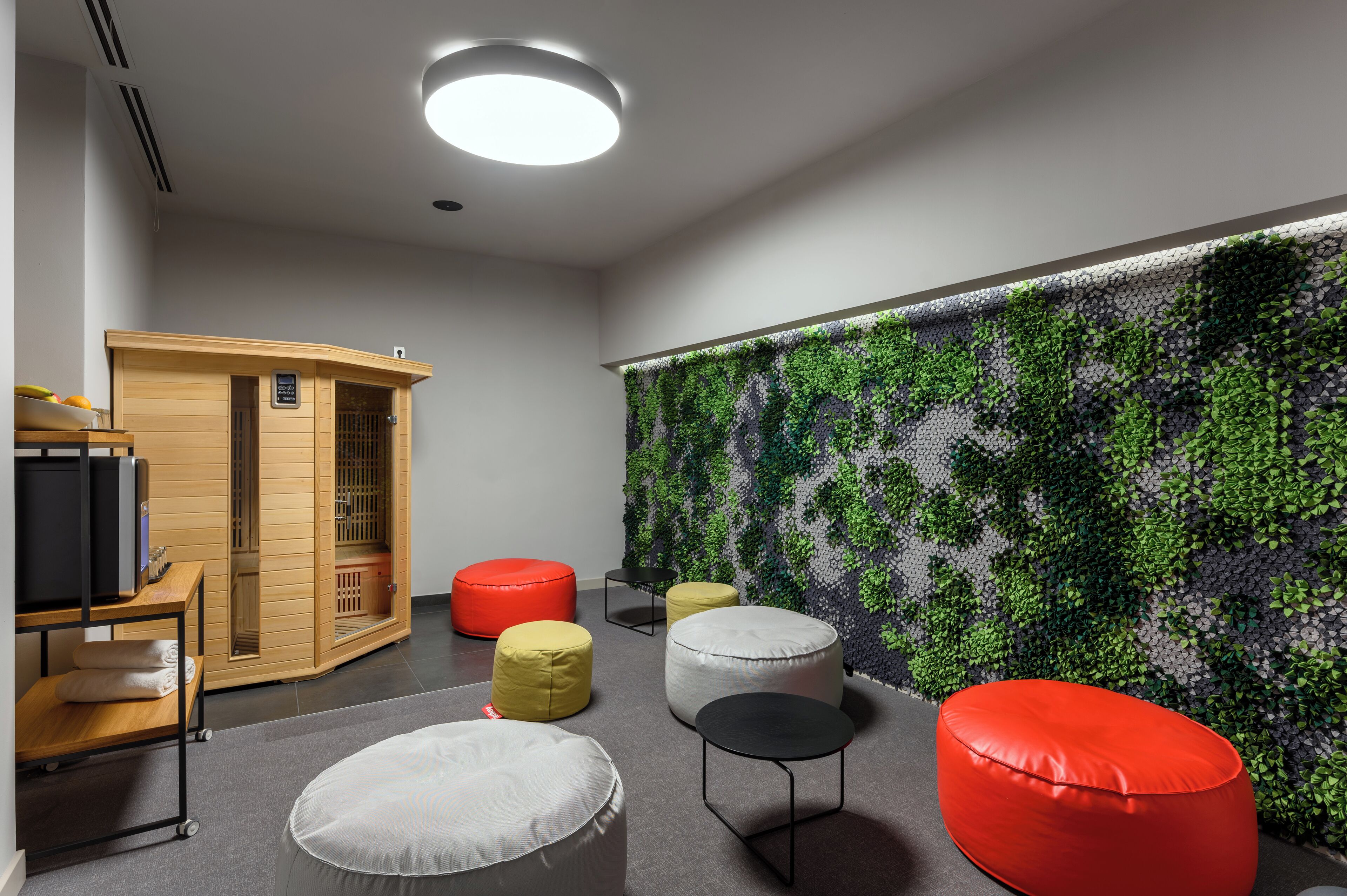 Una habitación moderna con pared verde, armario de madera y diferentes opciones de asiento.