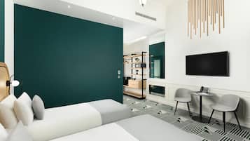 A modern hotel room with a large bed, a seating area with chairs, a TV mounted on the wall, and a small table with a phone.