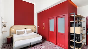 Habitación de hotel con cama, armario, una mesita y un perchero.
