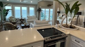 Una cocina moderna con isla, muebles blancos y vista al océano.