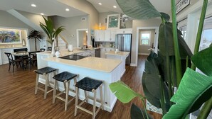 Una cocina amplia con una isla grande, taburetes de madera y un comedor con mesa y sillas.
