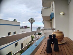 Un balcone con vista sul mare, un tavolo con teiera e due tazze, e una ringhiera.