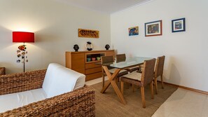 Un coin repas avec des meubles en osier, une table en verre et un buffet en bois orné de bols colorés.
