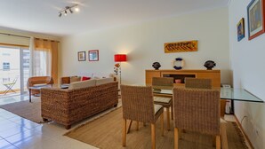 Ein Wohnzimmer mit Korbmöbeln, einem Glastisch und einer roten Lampe.