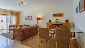 A living room with wicker furniture, a glass dining table, and a red lamp.