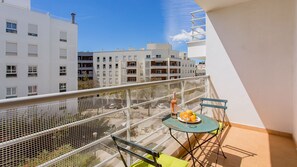 Ein Balkon mit Tisch, Stühlen und einer Weinflasche.
