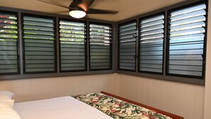 A bedroom with a bed, a ceiling fan, and windows with blinds. - Pikake ocean front 20 feet from ocean (Lahaina)