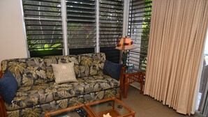 A living room with a sofa, two side tables, and a lamp. - Pikake ocean front 20 feet from ocean (Lahaina)