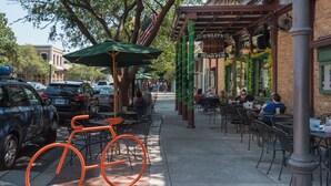 A street with outdoor seating at a restaurant, a bicycle, and parked cars. - 🌊Great Family Condo-Pool-Steps2Beach-2BR Villas On The Gulf C5🌊 (Pensacola Beach)