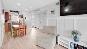 A modern living room with a beige sectional sofa, a flat-screen TV, and a bookshelf. - 🌊Great Family Condo-Pool-Steps2Beach-2BR Villas On The Gulf C5🌊 (Pensacola Beach)