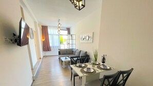 Ett modernt vardagsrum med en matplats, med en soffa, ett matbord med plats för fyra personer och en trappa som leder upp till en övre våning.