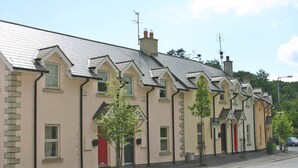 A row of traditional buildings with gabled roofs and chimneys, likely residential or small commercial properties. - Churchmount Holiday Home Roundwood (Roundwood)