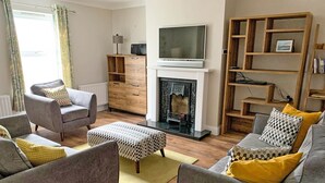A living room with a fireplace, a television, and a bookshelf. - Churchmount Holiday Home Roundwood (Roundwood)
