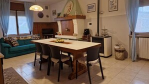 A cozy living room with a wooden dining table, a sofa, and a TV. - Delightful Apartment Tourist Rental (Lonigo)