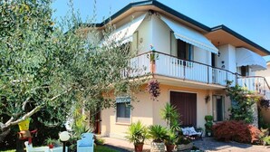 A two-story house with a balcony, a small garden with potted plants, and a white fence. - Delightful Apartment Tourist Rental (Lonigo)