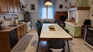 A compact kitchen with wooden cabinets, a dining table with chairs, a built-in oven, and a TV.