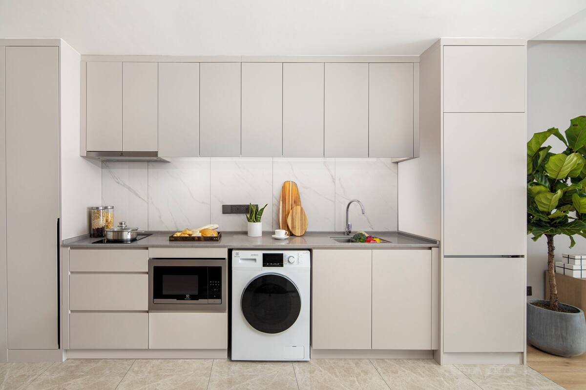 A modern kitchen with a built-in washer and dryer, a microwave, and a sink.