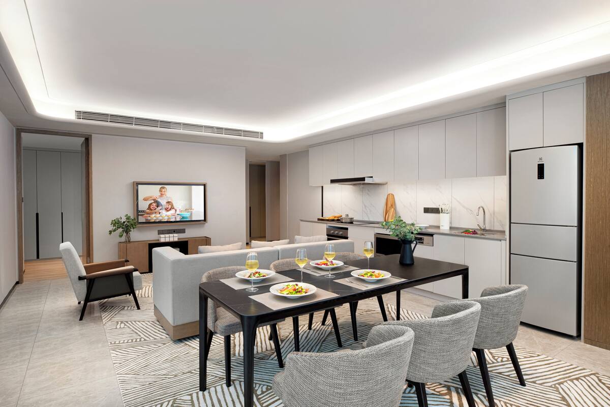 A modern kitchen with a dining area, featuring a central island, built-in appliances, and a flat-screen TV.
