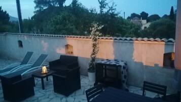 Une terrasse extérieure avec des chaises longues, une table et une plante en pot.
