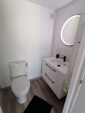 Een compacte, moderne badkamer met toilet, wastafel en spiegel.