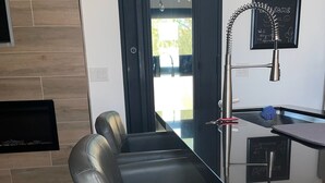Una cocina moderna con una isla de vidrio, un banco empotrado y una pizarra con escritura.