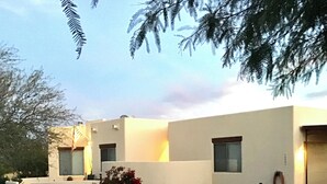 Un edificio moderno con tejado plano, ventanas amplias y un jardín cuidado con rocas y plantas.