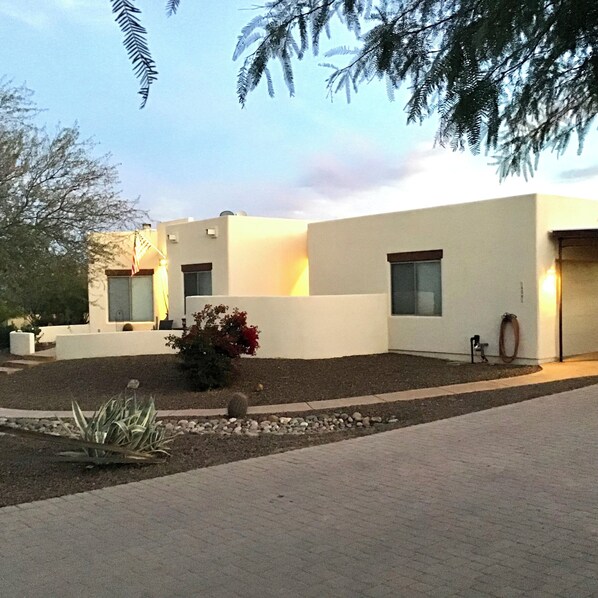 Un edificio moderno con tejado plano, ventanas amplias y un jardín cuidado con rocas y plantas.