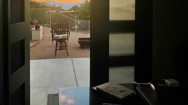 Una habitación con vista a una puesta de sol desde un balcón.