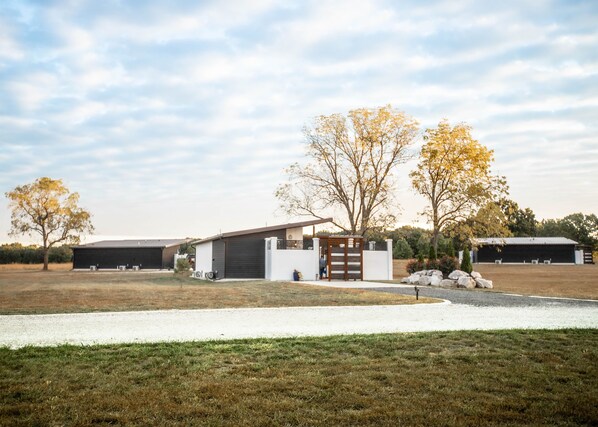 A modern house with a garage, a small garden, and a large open field.