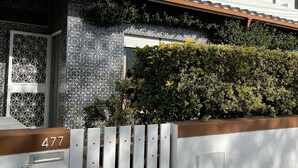 A residential building with a white exterior, a tiled entrance, and a number '477' on the wall.