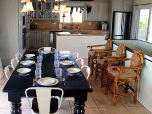 A dining area with a black table set for six, surrounded by wicker chairs. - Panoramic Gulf Views | Heated Pool | Beach (Captiva)