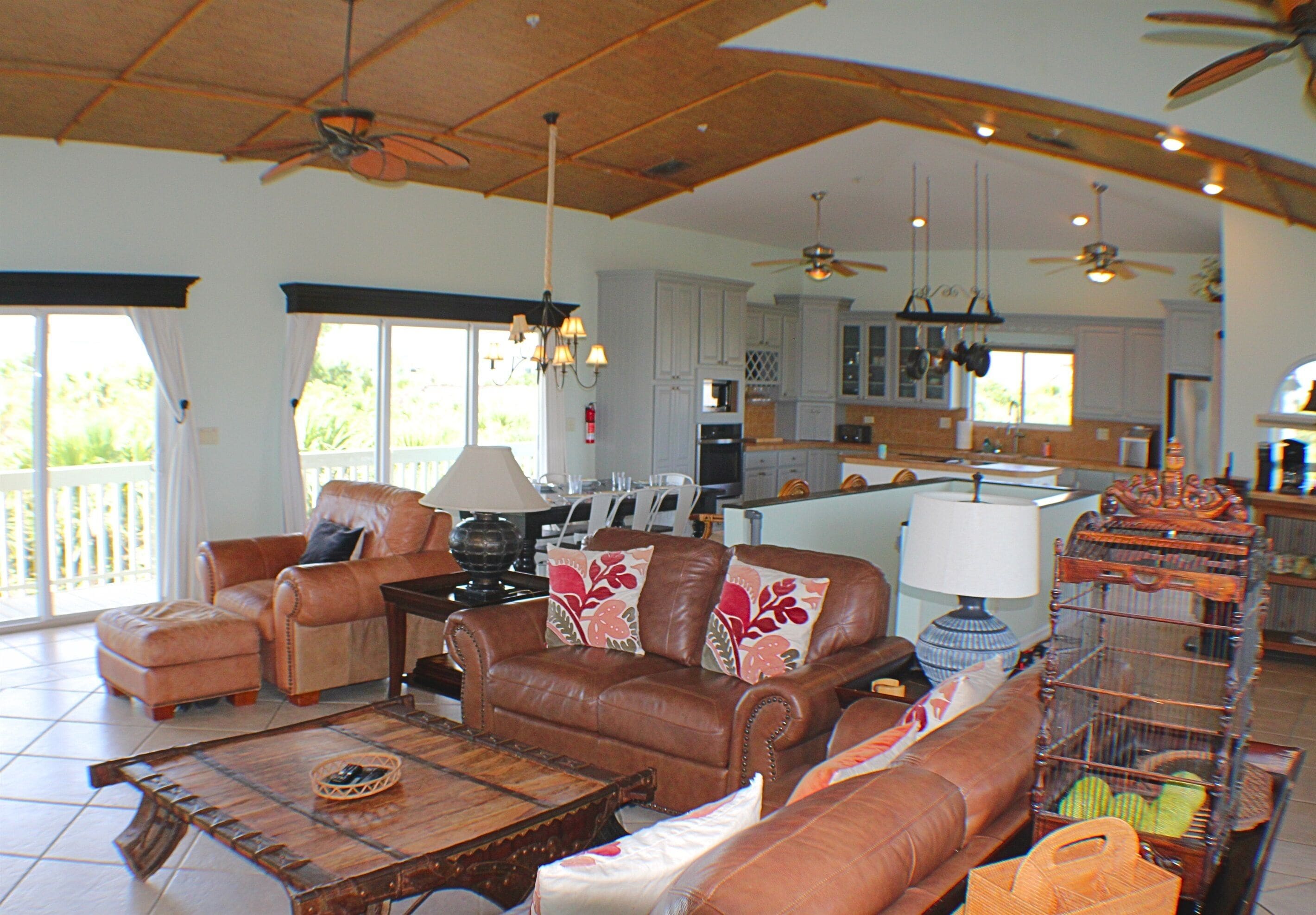 A spacious living room with leather sofas, a wooden coffee table, and a ceiling fan.
