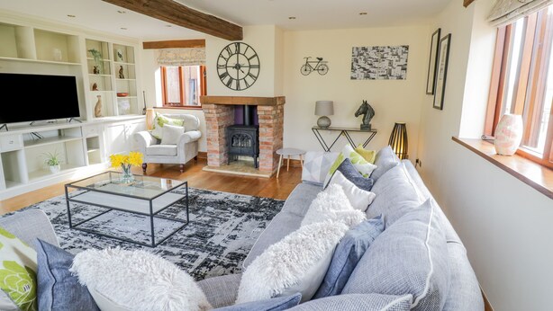A living room with a sofa, armchairs, a TV, a fireplace, and a bookshelf. - The Stables (Stourbridge)