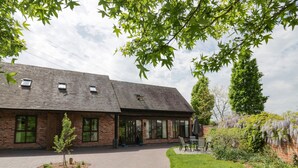 A brick building with a covered patio and outdoor seating area. - The Stables (Stourbridge)