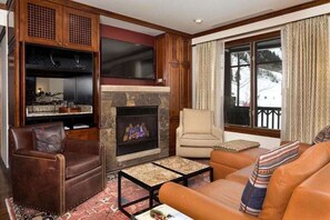 Cozy living room with a fireplace, comfortable seating, and a view of the outdoors.
