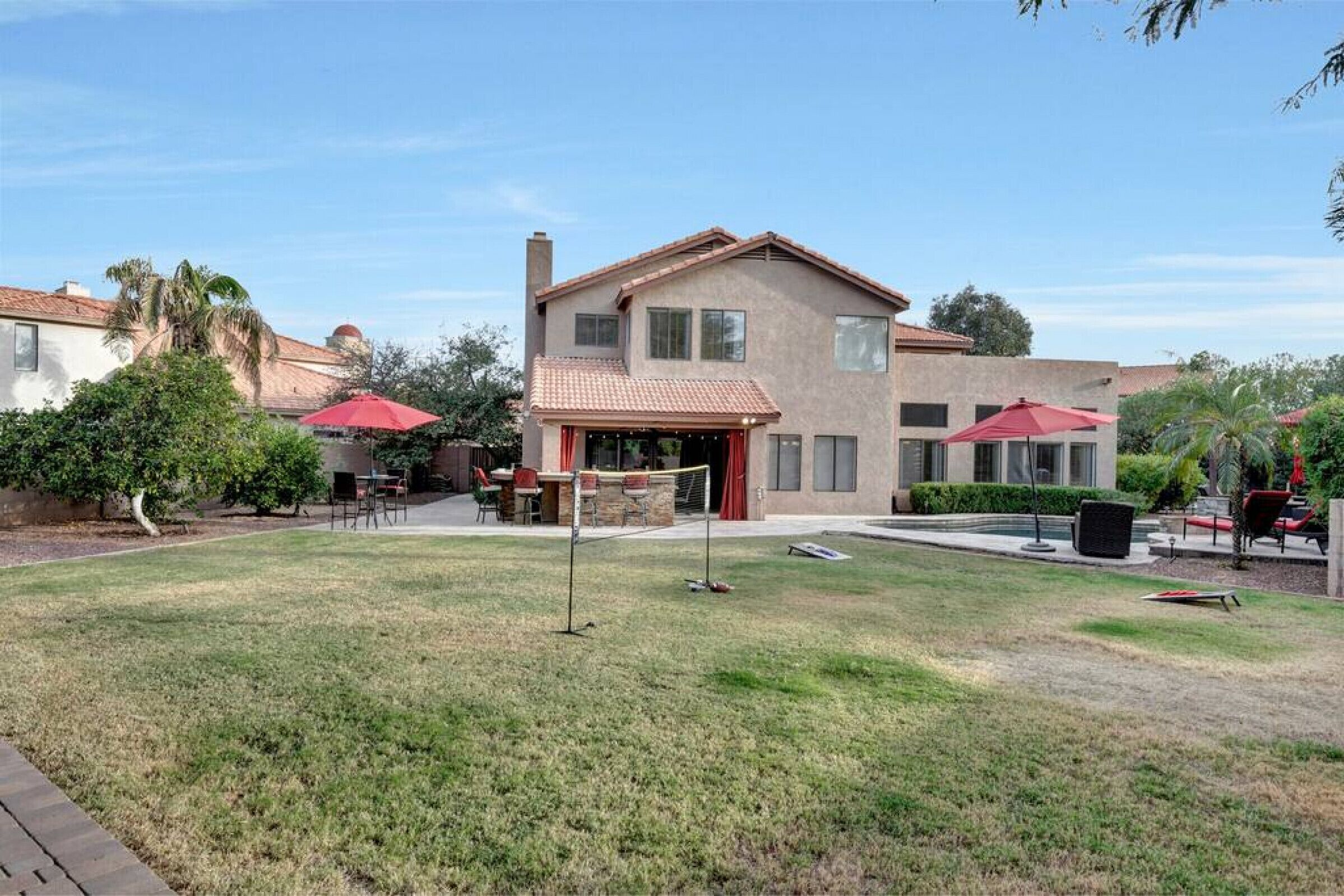 A two-story house with a patio area, outdoor seating, and a well-maintained lawn.