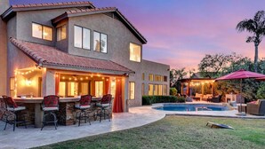 A two-story house with a patio area, a pool, and outdoor seating. - Extravagant Backyard & Dazzling Interior Concepts (Scottsdale)