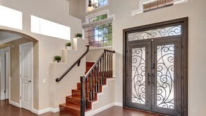A staircase with wooden steps and a metal railing, leading to a door with decorative glass panels. - Extravagant Backyard & Dazzling Interior Concepts (Scottsdale)